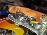 Close-up of a guitar's control knobs and wiring on a colorful guitar body.