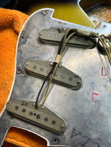 Close-up of a guitar's pickups and wiring on a textured surface.