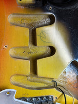 Close-up of a guitar's bridge and headstock with visible wear.