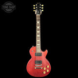 A red electric guitar with gold tuners and gold control knobs, shown vertically against a solid black background. A Tone Shop watermark is visible in the top-left corner.