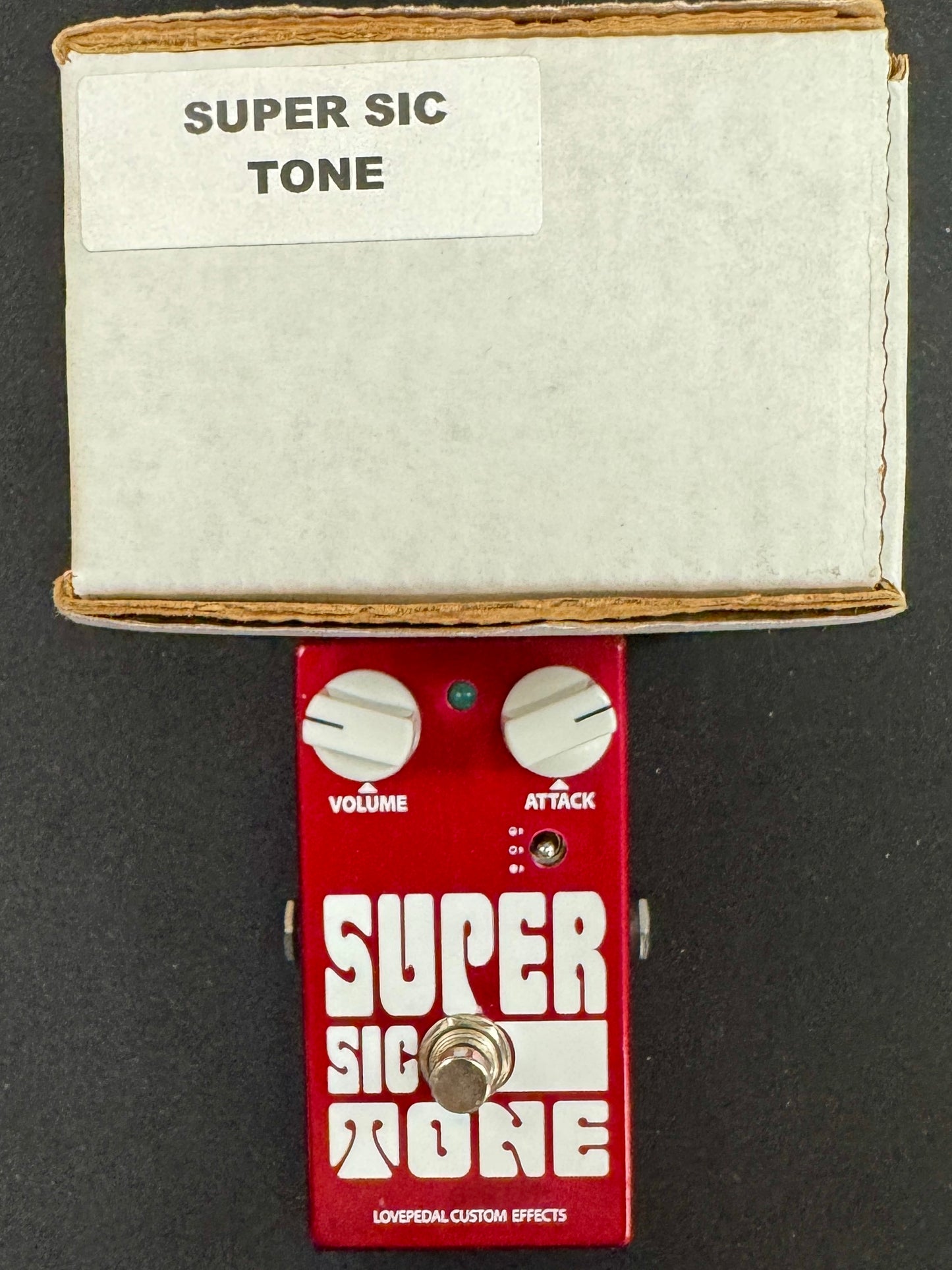 Red guitar effects pedal with 'Super Sic Tone' and 'Super Sic More' labels on a black background