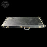Black guitar case with gold hardware on a black background, featuring a 'Tone Shop' logo.