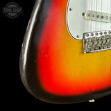 Close-up of a guitar with a sunburst finish and 'Tone Shop' logo.