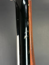 Close-up of a black gun stock with a brown wood forend on a dark gray background.