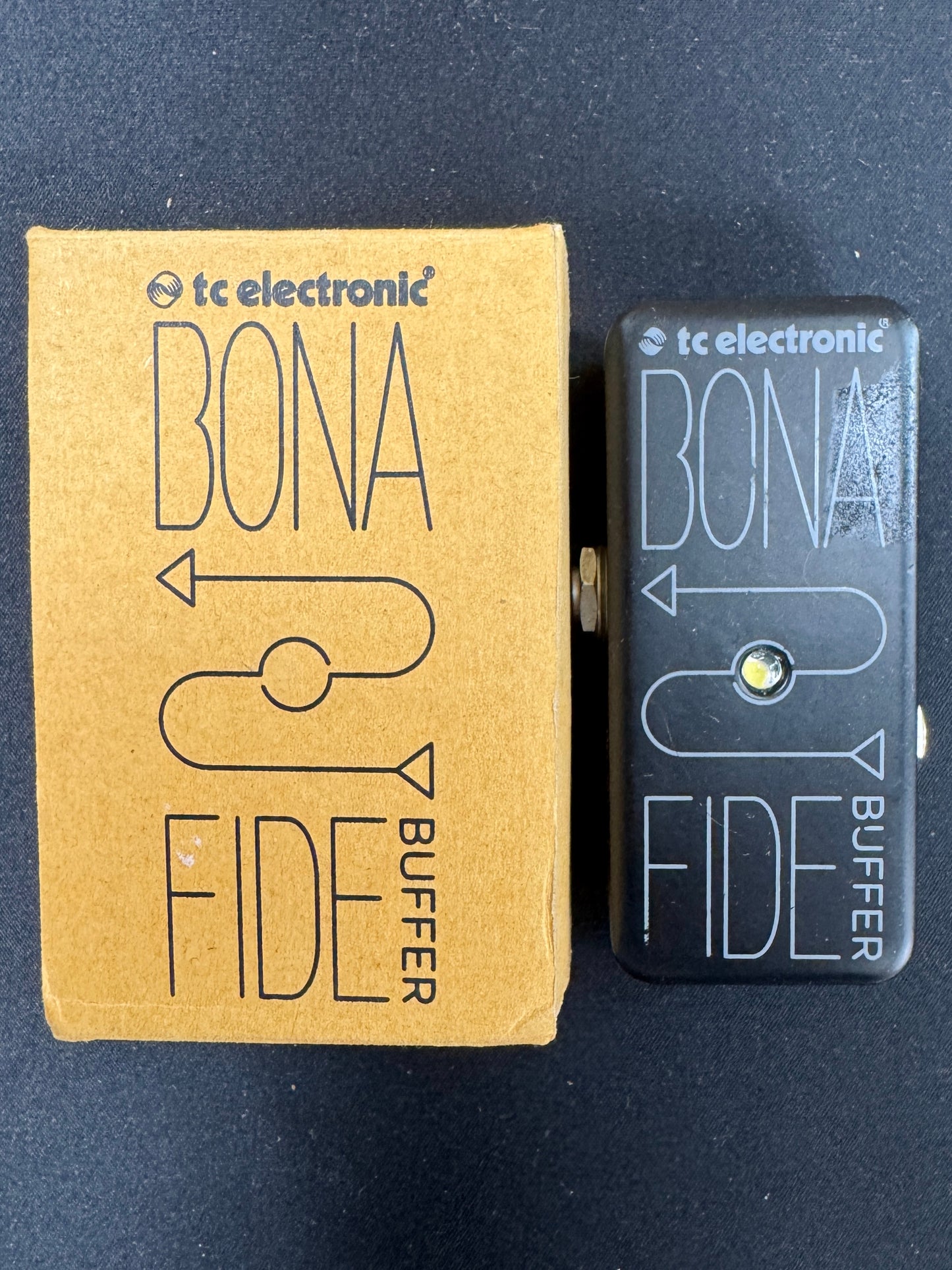 TC Electronic Bona Fide buffer pedal next to its packaging on a dark background
