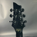 Close-up of a black guitar headstock with tuning pegs on a gray background