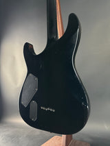 Black electric guitar body on a reflective surface with a neutral background
