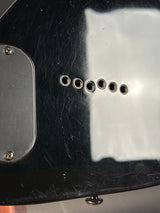 Close-up of a guitar's control knobs and body with visible wear.