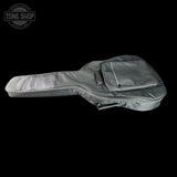 A gray guitar gig bag with a front zippered pocket, shown from a side profile view against a solid black background. A 'TONE SHOP' logo watermark is visible in the top-left corner.