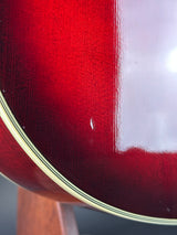 Close-up of a glossy dark red wooden surface with visible wood grain and a light-colored edge stripe.