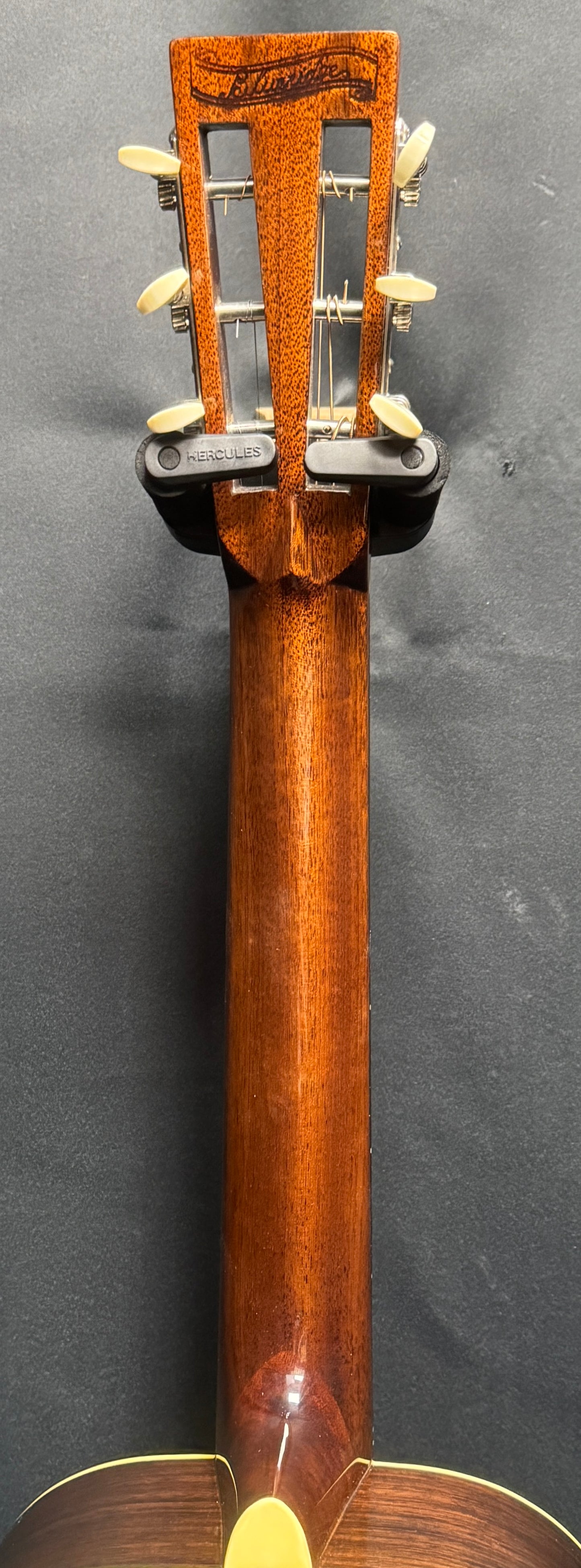 Close-up of a guitar's neck and headstock on a dark background