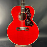 Red acoustic guitar with decorative inlay on a dark background