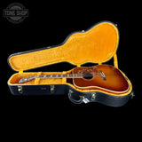 Acoustic guitar in a black case with orange interior on a black background, featuring 'Tone Shop' logo.