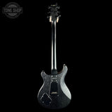 A black electric guitar shown from the back against a solid black background, with a Tone Shop watermark in the upper left corner.