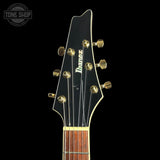 Close-up of an Ibanez electric guitar headstock and neck against a solid black background, featuring gold tuning pegs and a dark wood fretboard.