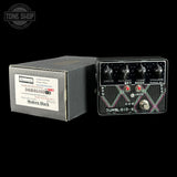 Guitar effects pedal with 'Dumbleloid-X' branding next to its packaging on a black background.