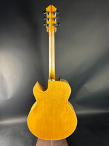 Side view of a yellow acoustic guitar on a dark background