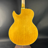 Back view of a yellow acoustic guitar on a dark background