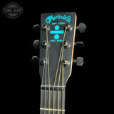 Close-up of a Martin & Co acoustic guitar headstock with a black finish and bright blue logo text, shown against a black background with a Tone Shop watermark in the upper left.