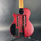 The back of a Fender Stratocaster electric guitar in a distressed red finish, mounted on a stand against a dark gray background.