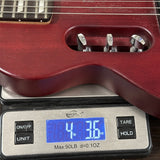 Close-up of a red guitar body resting on a digital scale displaying 4 lbs 36 oz, with the scale showing brand text 'Welch' visible.
