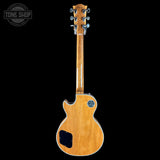 A natural wood electric guitar shown from the back against a solid black background, with a Tone Shop watermark in the upper left corner.