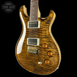 Wooden electric guitar with a wavy finish on a black background, featuring the Tone Shop logo.