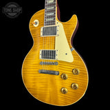 A Les Paul style electric guitar with a natural flamed maple top, cream pickguard, and gold hardware, shown against a solid black background with a Tone Shop watermark in the top-left corner.