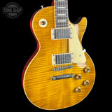 A close-up of an electric guitar body in a natural maple wood finish with a cream pickguard, dual humbucker pickups, and gold-tone controls, shown against a black background with a Tone Shop watermark.
