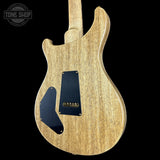 Back view of a wooden electric guitar with a black pickguard on a black background, featuring 'Tone Shop' branding.