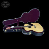 Acoustic guitar in an open case with 'Tone Shop' logo in the corner.