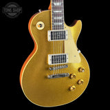 A gold glitter electric guitar with a cream pickguard, dual humbucker pickups, and gold hardware, shown against a solid black background with a Tone Shop watermark in the top left corner.