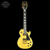 A yellow Gibson Les Paul Custom electric guitar with gold hardware, shown against a solid black background. A 'TONE SHOP' watermark is visible in the top-left corner.