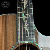 Close-up of a guitar's fretboard with inlaid patterns on a black background, featuring the Tone Shop logo.