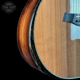 Close-up of a wooden acoustic guitar with a brand logo in the corner.