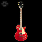 A red Gibson electric guitar with a cream pickguard and gold hardware, shown against a solid black background with a Tone Shop watermark in the top-left corner.