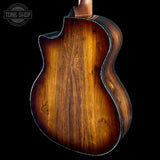 Close-up of a wooden guitar body with a dark brown finish on a black background, featuring the Tone Shop logo.