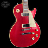 A red Gibson Les Paul Custom electric guitar with gold hardware and a cream pickguard, shown against a solid black background. A 'Tone Shop' watermark is visible in the top-left corner.