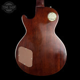 The back of a vintage Gibson electric guitar with a glossy dark brown wood finish, featuring a gold-toned circular plate and a tan pickguard on a black background.