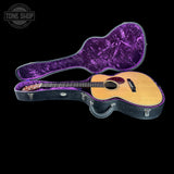 Acoustic guitar in a purple-lined case on a black background with 'Tone Shop' logo.