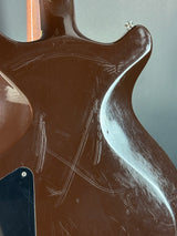 Close-up of a guitar's back with visible wear and tear on a gray background