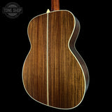 Close-up of a wooden acoustic guitar on a black background with 'Tone Shop' logo.