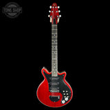 Red electric guitar with a black pickguard on a white background
