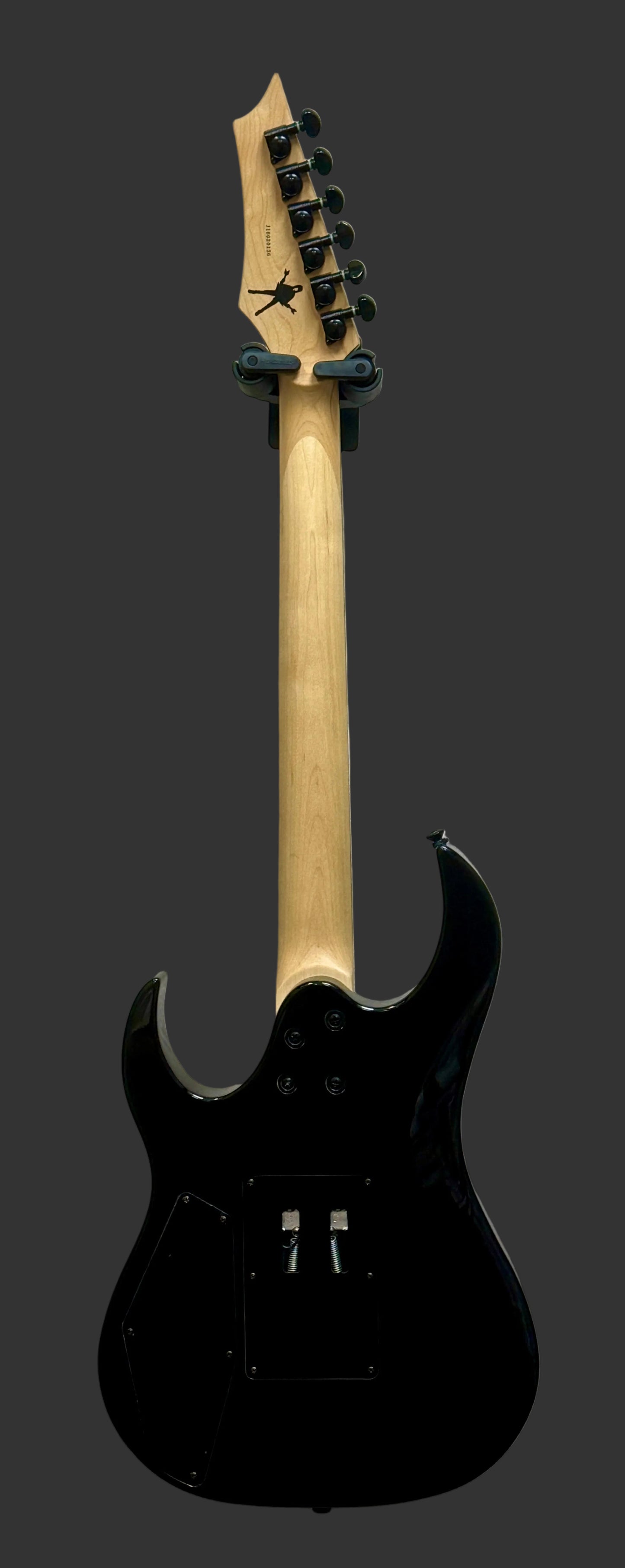 Black electric guitar with a wooden neck against a light gray background