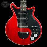 Red electric guitar with a black pickguard on a black background, featuring the Tone Shop logo.