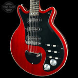 Red electric guitar with a black pickguard on a black background, featuring 'Tone Shop' logo.