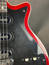 Close-up of a black electric guitar with red pickguard