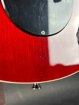 Close-up of a red guitar with a black pickguard on a blurred background
