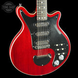 Red electric guitar with black pickguard on a black background, featuring 'Tone Shop' logo.