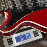 Red electric guitar on a digital scale displaying weight